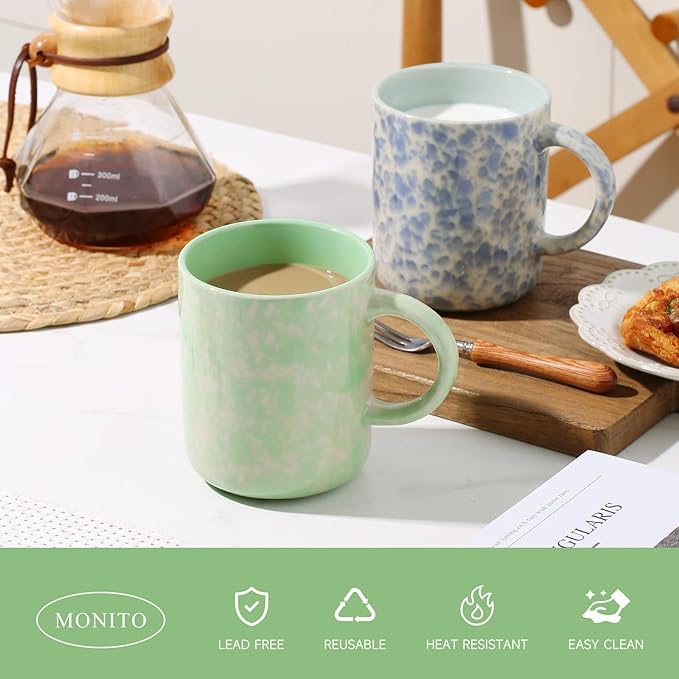 Ceramic coffee mug with mint green finish and handle; blue speckled mug behind