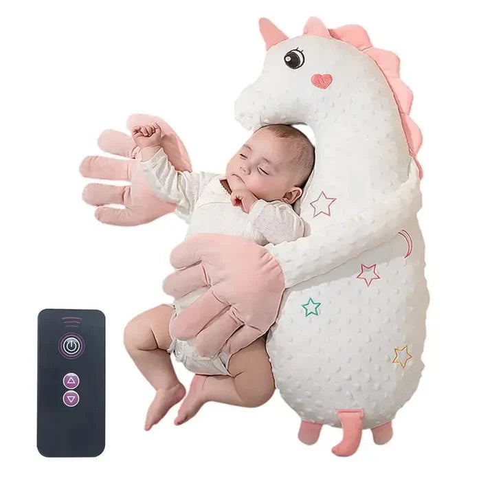 Pink plush unicorn sleep soother pillow with baby cuddled and remote controller nearby.