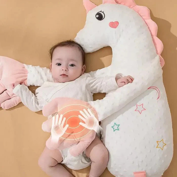 Pink plush unicorn sleep soother with baby lying back in the body cutout.