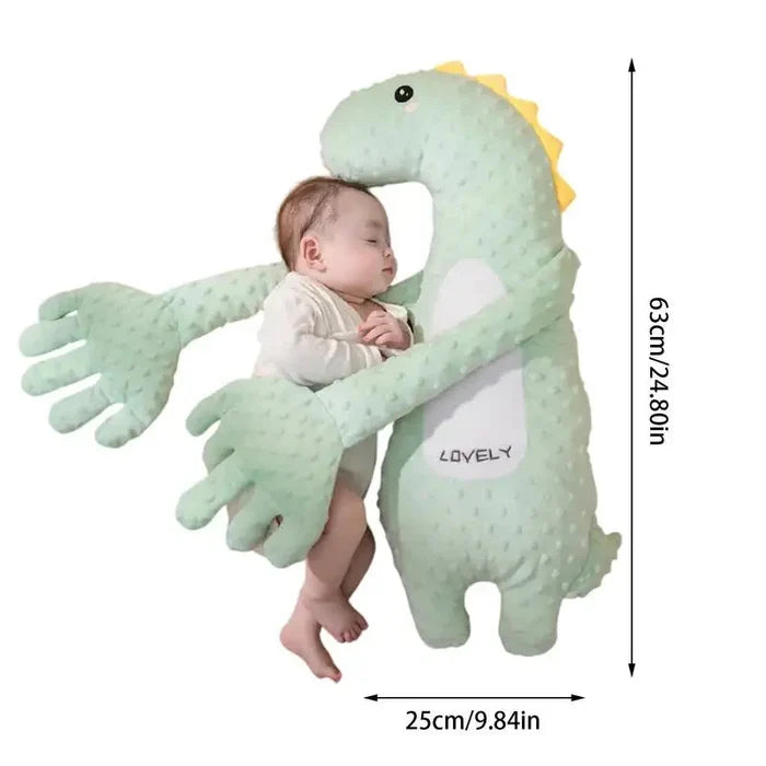 Green plush dinosaur sleep soother pillow with yellow crest, supporting a baby.