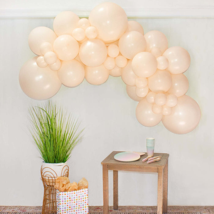 Blush balloon garland arch with pale cream balloon clusters in a curved shape
