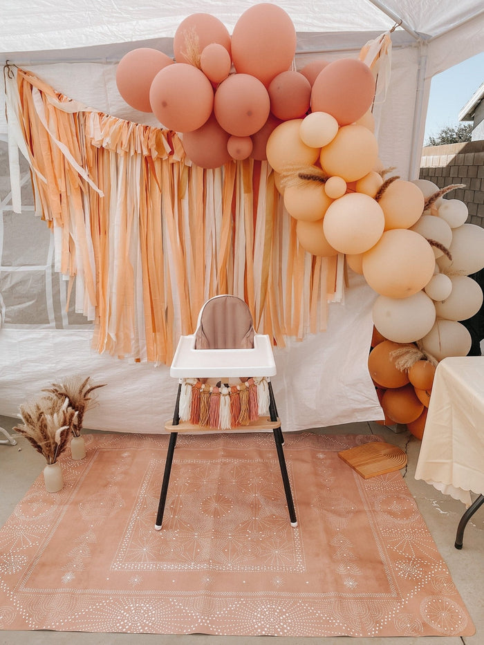 Balloon garland arch outdoors with blush and peach balloon clusters on a frame