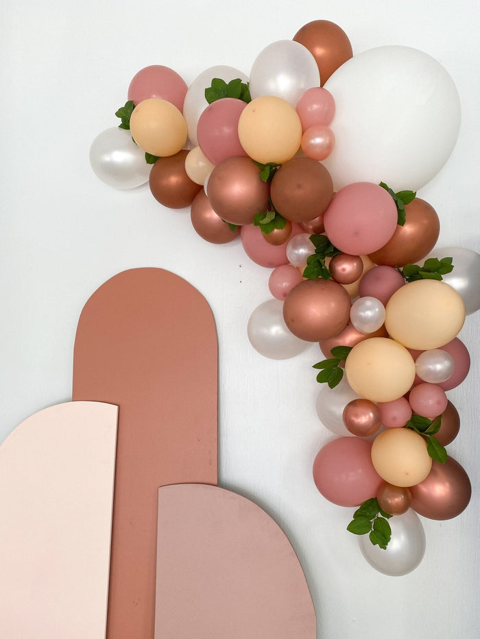 Balloon garland wall piece with mixed pink, brown, and cream balloons with greenery