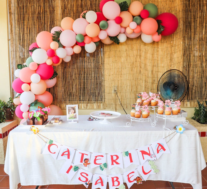 Balloon garland arch over party table with pink, cream, and coral balloon clusters