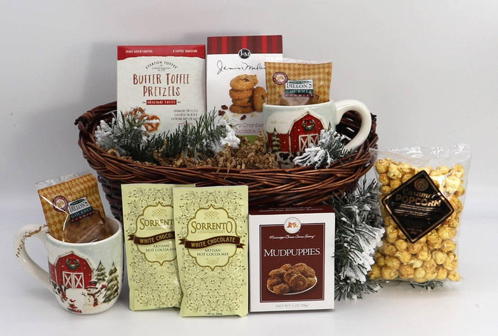 Wicker holiday gift basket with farmhouse mugs, wrapped snacks, and pine greenery