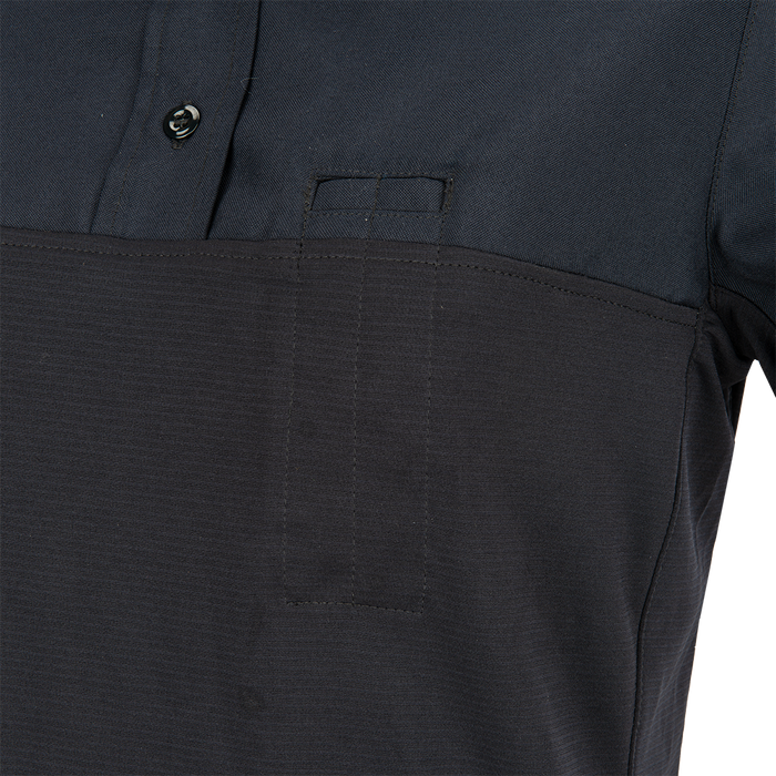 Close-up of a dark navy blue polo shirt featuring a contrasting textured lower section a small pocket and subtle stitching details