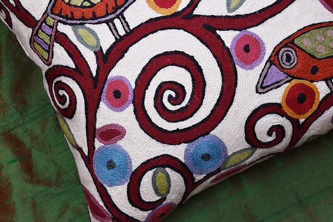 White pillow cover corner with colorful bird and spiral embroidery detail