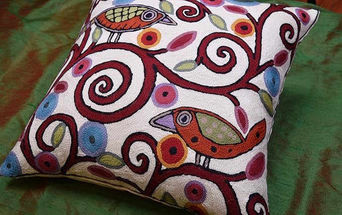 White pillow cover with bird motifs and red, blue, and yellow swirl embroidery