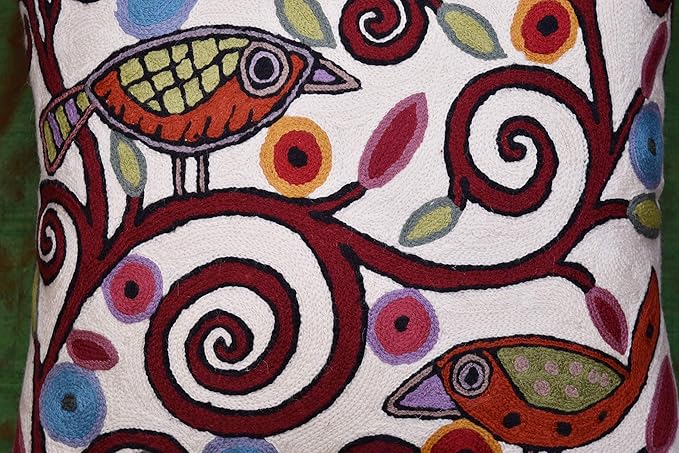 White pillow cover close-up of birds and spiral threadwork in red and blue