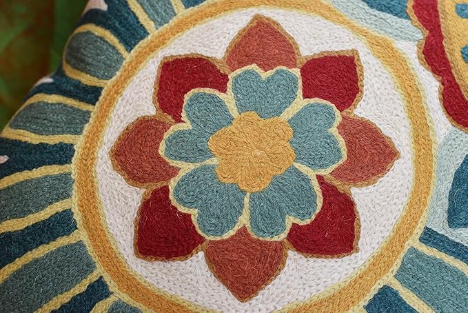 Close-up embroidered rosette flower on cream pillow cover with teal, red, and gold center