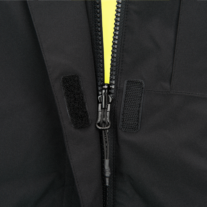 Close-up photograph showing a black jacket detail with a bright yellow zipper and black velcro closures