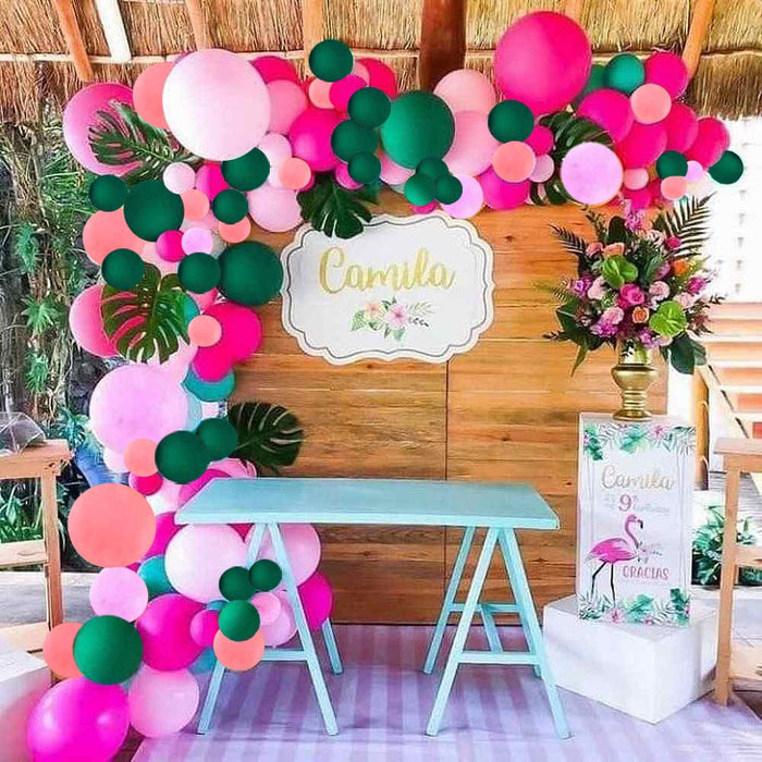 Wild safari party backdrop with pink, green, and white balloon garland and jungle decor