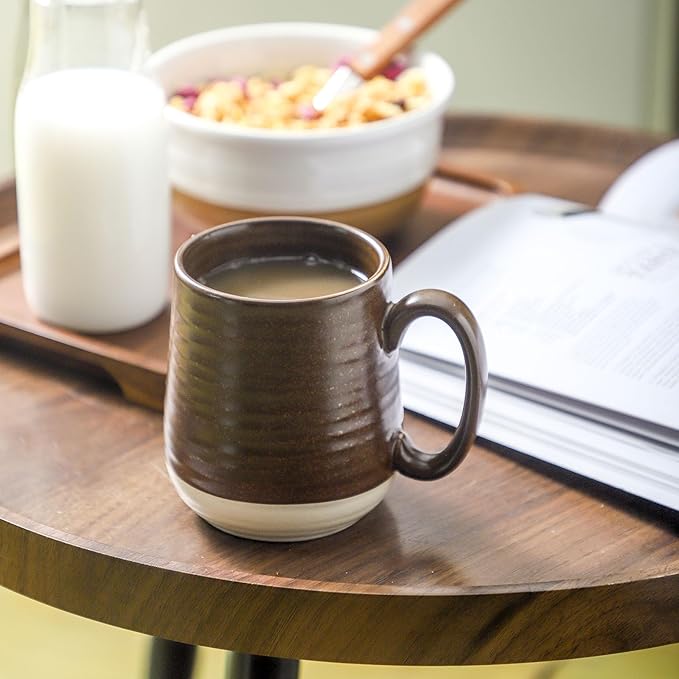 Stoneware coffee mug with handle in brown textured glaze on wooden table