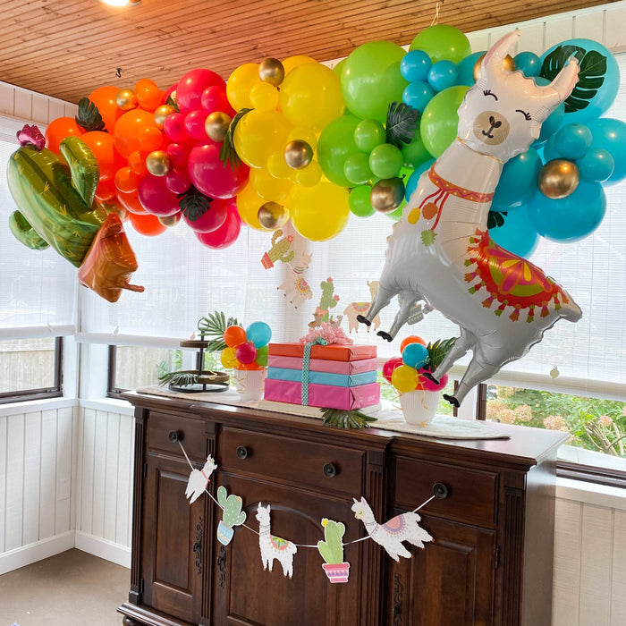 Llama-shaped balloon standing on table with colorful balloon bunches around