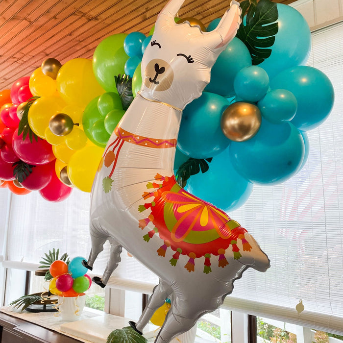 Llama-shaped balloon close-up with white body, green leaf wings, and tassel skirt