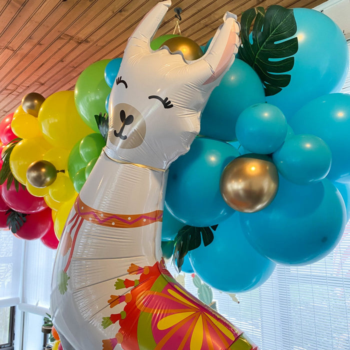 Llama-shaped balloon close-up with white body, green leaf wings, and red-orange skirt