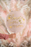 Pink round foil balloon with gold “love you mom” lettering and attached string