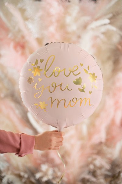 Pink round foil balloon with gold “love you mom” lettering and attached string