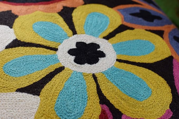 Close-up embroidered daisy flower with blue-green petals and white center on dark fabric