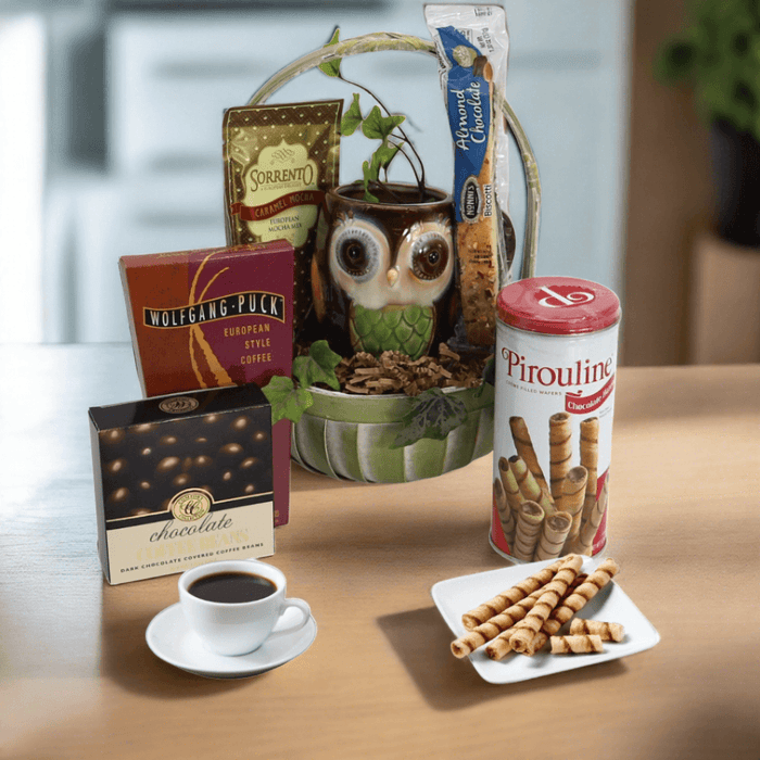 Gift basket with owl-themed holder, coffee tins, chocolate box, and wafer cookies