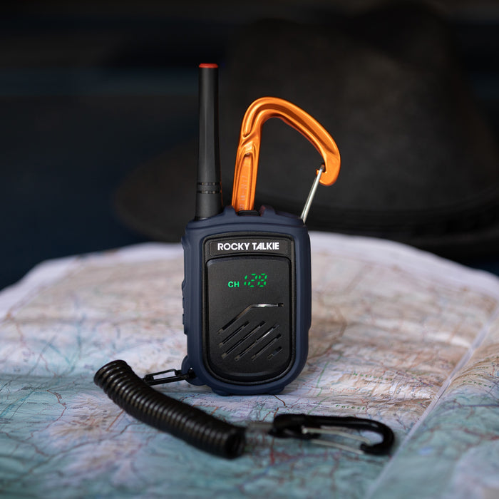 Rocky Talkie Mountain Radio with carabiner attachment and coil leash sitting on a map