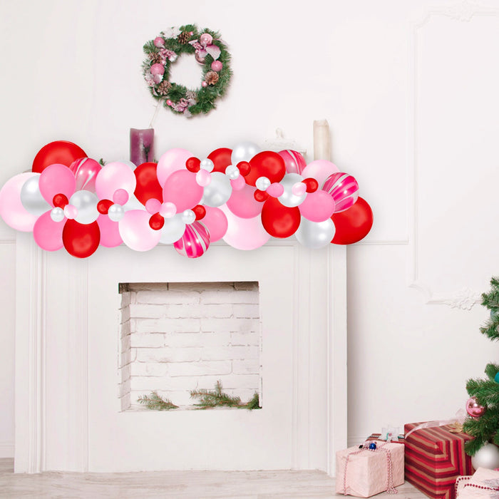 Pink, red, and white balloon garland forming a wide doorway arch
