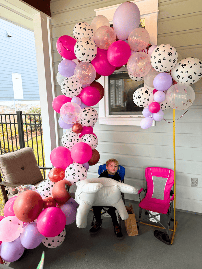 Balloon garland arch with pink, white, and light purple balloons plus dog-print accents
