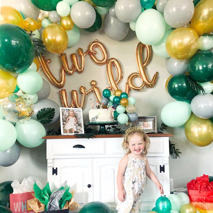 Latex balloon garland with gold and green balloons framing foil letters