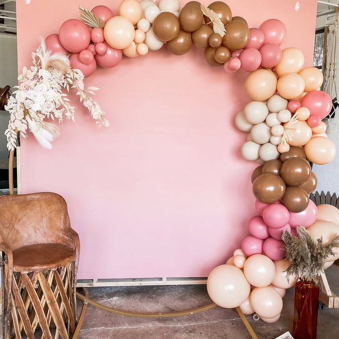 Balloon arch with pink, peach, and gold latex balloons plus small white accents