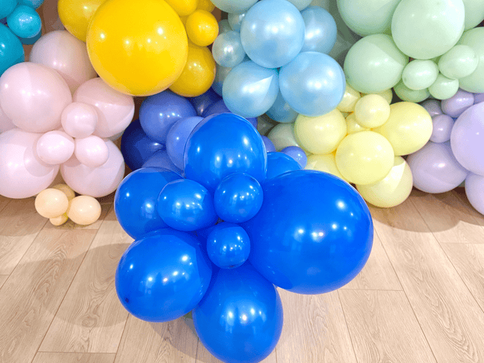 Blue periwinkle balloon cluster among mixed-color latex balloons, glossy spheres
