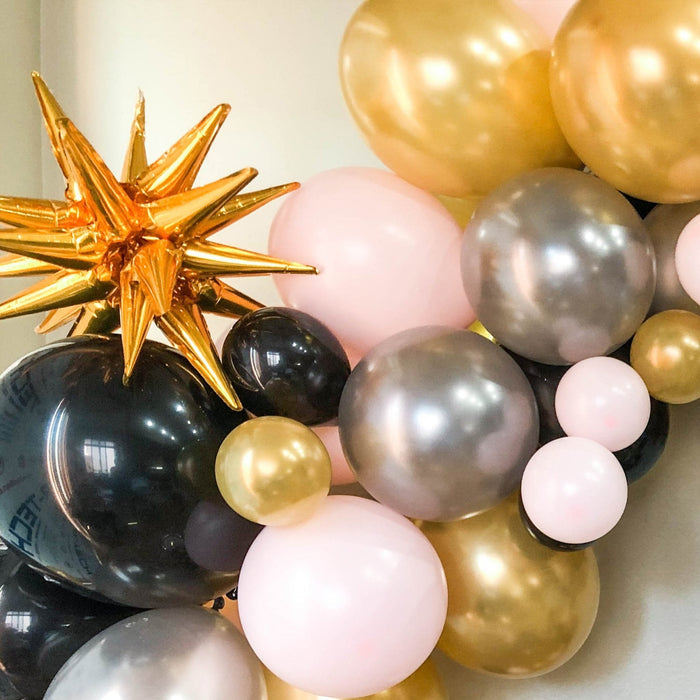 Assorted latex balloons with gold star topper and silver, pink, and black balloons