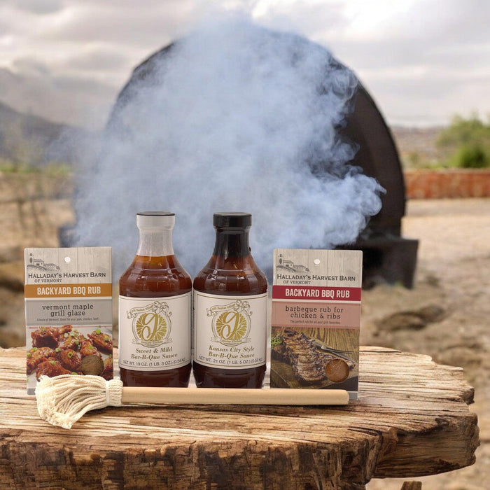 BBQ gift set on wooden board with two sauce bottles, two rub packets, and smoke
