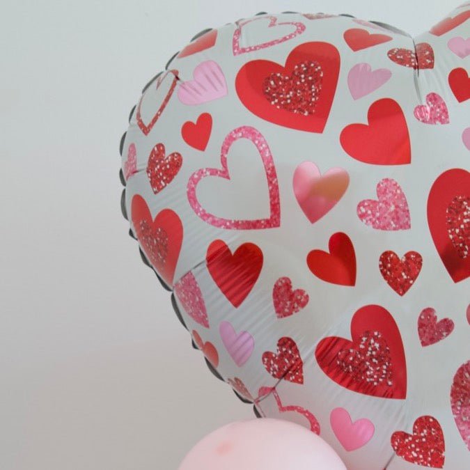 Heart foil balloon with red and pink heart patterns and light pink balloon cluster below