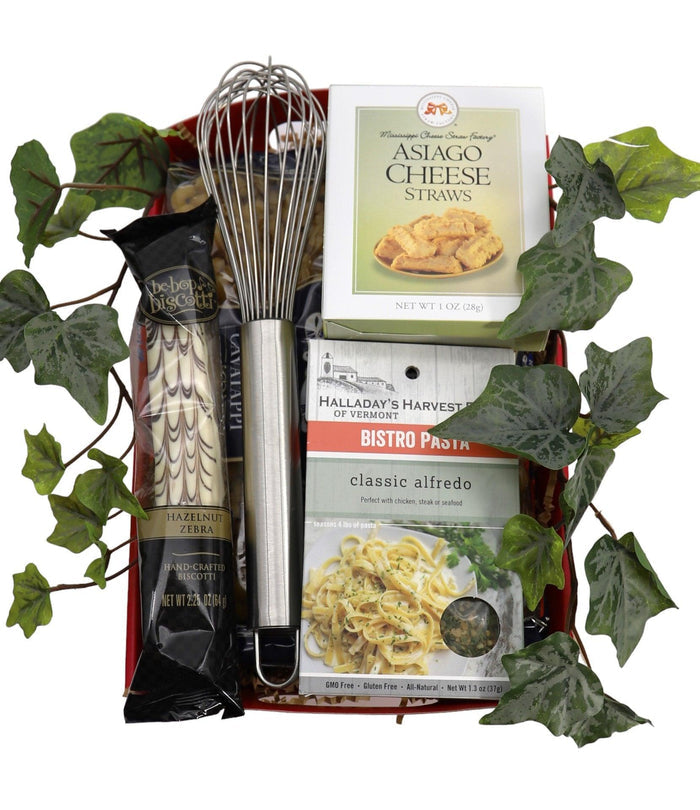 Pasta gift tray with metal whisk, pasta boxes, sauce packets, and assorted foods