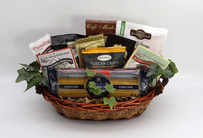 Italian gourmet gift basket with pasta, crackers, and assorted snack packs plus greenery