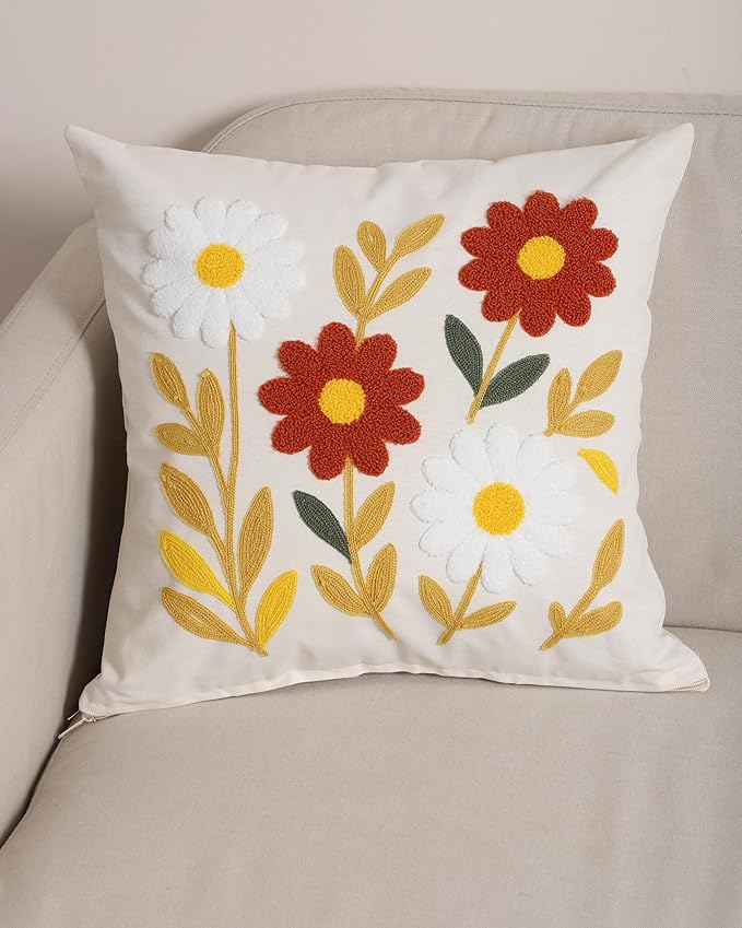 White floral cushion cover with punch-needle daisies and leaves on a sofa