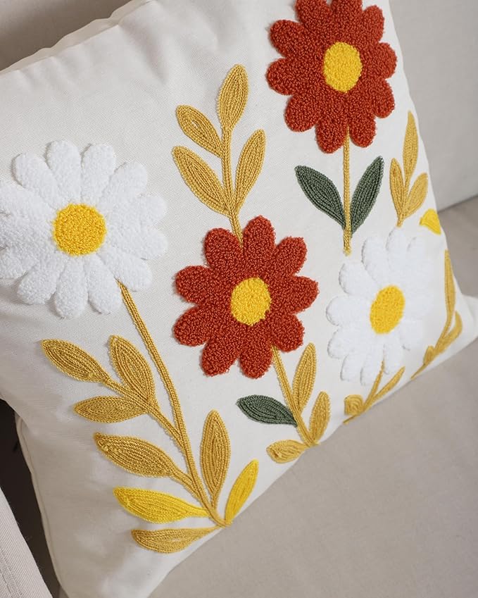 Corner view of white pillow cover with large red flower and yellow leaf embroidery