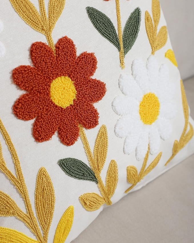Close-up of white pillow cover with red flower center, green leaves, and yellow stems