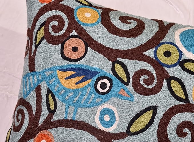 Embroidered bird and swirl motif on teal blue pillow cover