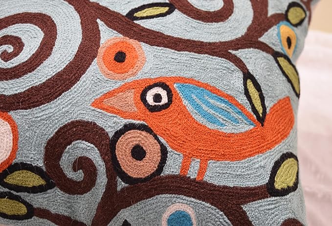 Close-up of embroidered orange, blue, and brown bird pattern on pillow cover