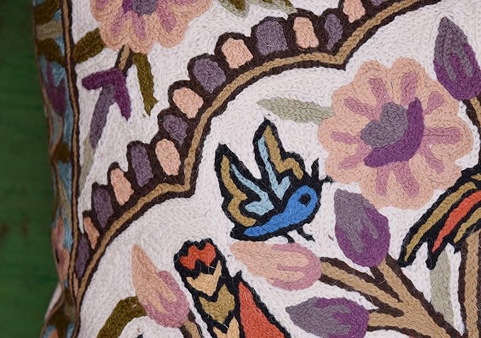 Close-up of stitched birds on a tree branch within a floral pillow cover border