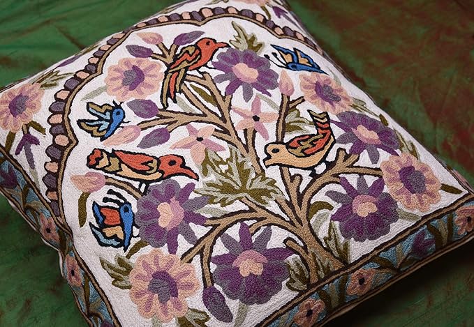 Corner view of embroidered tree-and-birds pillow cover with purple floral accents