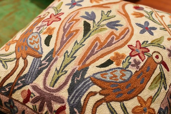 Cream pillow cover detail with two birds and floral motifs in warm orange tones