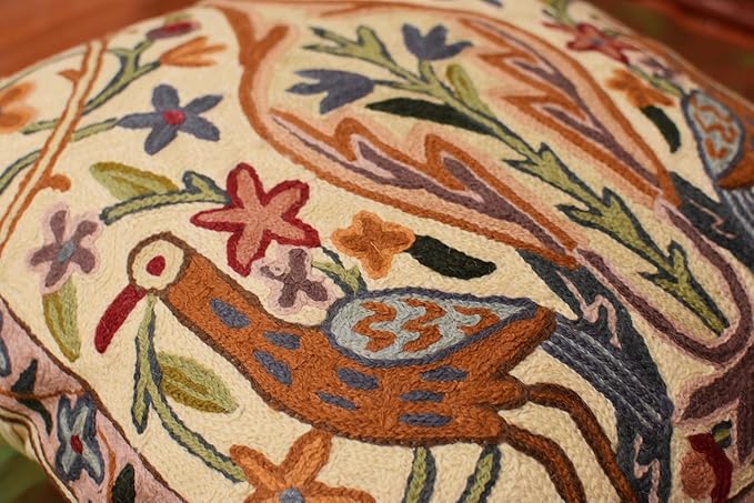 Cream pillow cover close-up of embroidered bird with flowers and leaves