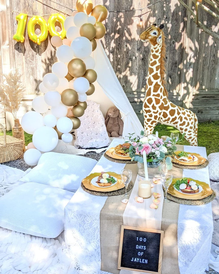 White balloon garland with tall balloon cluster and gold accents outdoors