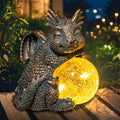 Sleeping blue dragon figurine holding a glowing crackled globe solar light for garden